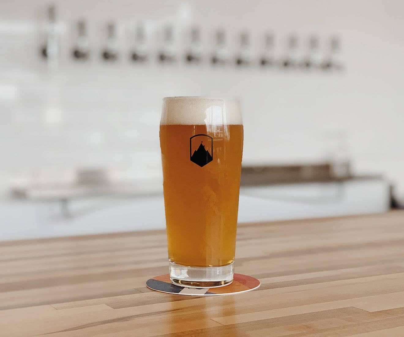 Ambitious Ales Brewery, pint on wooden bar with tabs in background