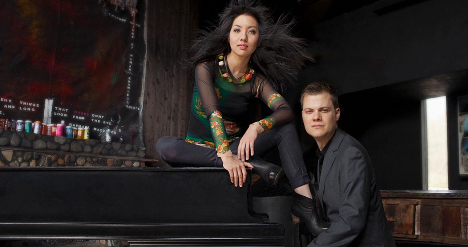 Anderson & Roe, piano duo posing with piano, featured image