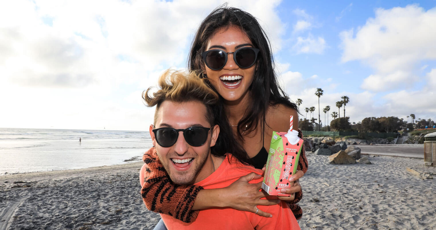 BeatBox Beverages, couple on beach, piggy back, featured image
