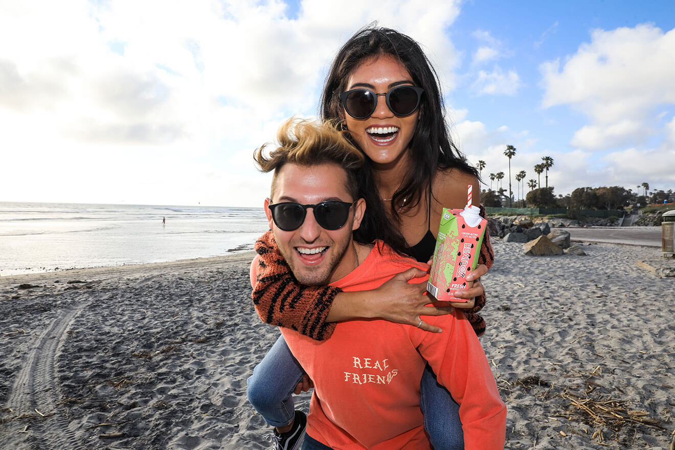 BeatBox Beverages, couple on beach, piggy back