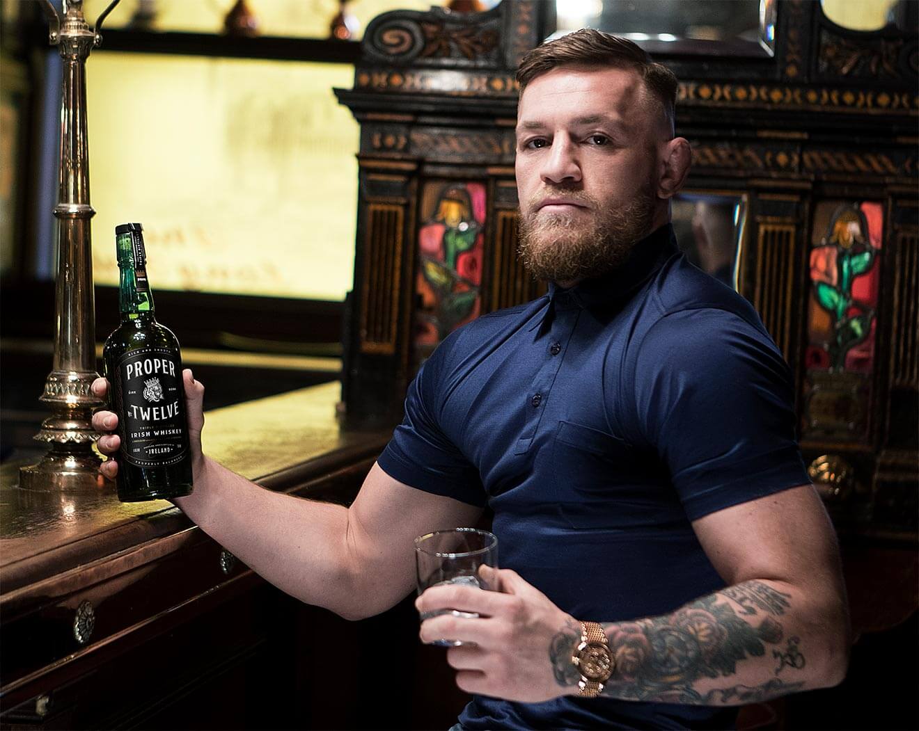 Connor McGregor's Irish Whiskey, holding bottle at bar