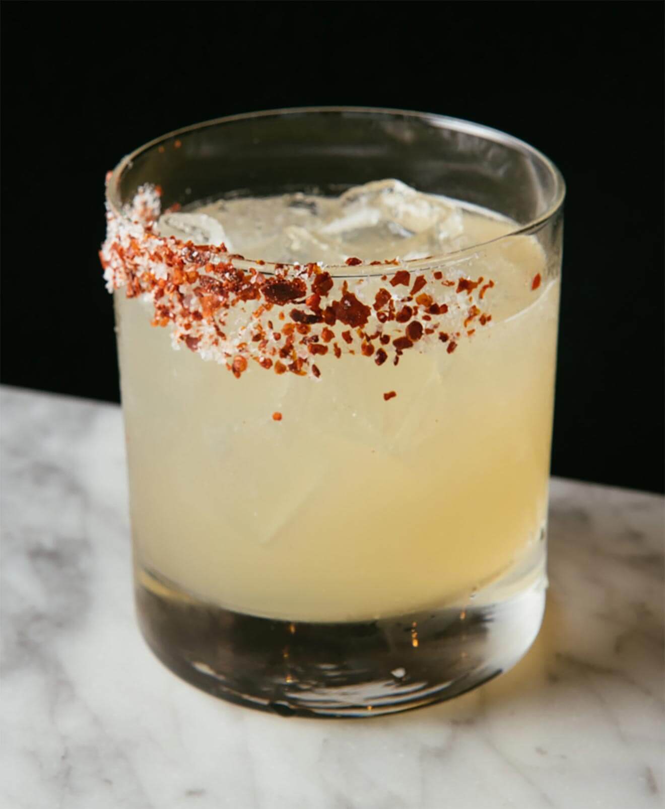 Dionysus Revival cocktail with salt garnish, marble table