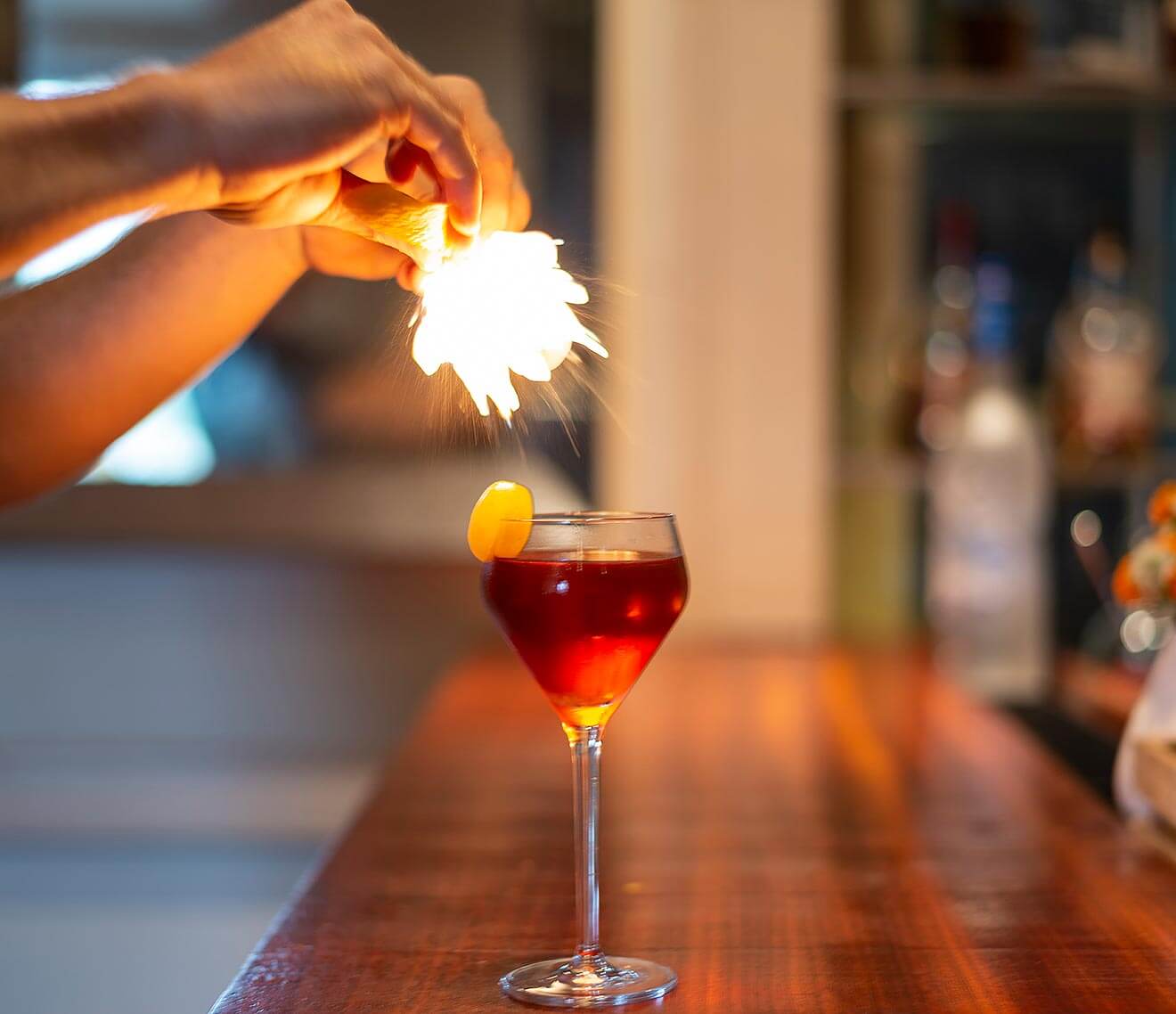 Eau de Vie cocktail with bartender adding garnish with flare
