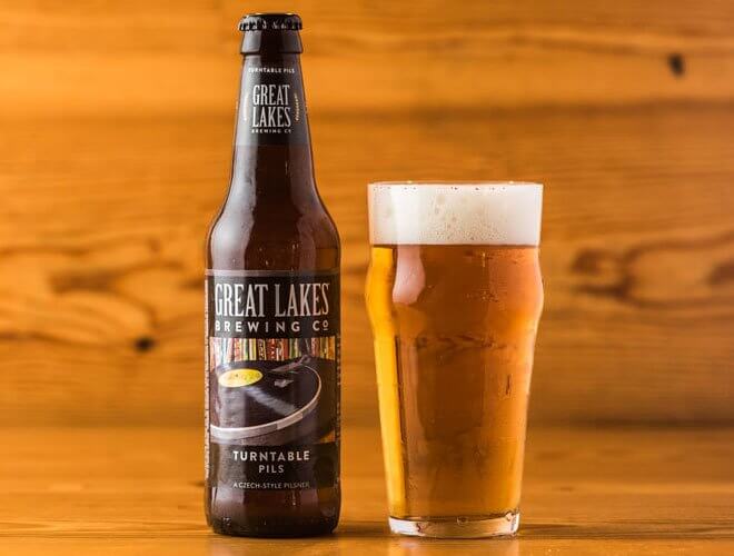Great Lakes Brewing Co. Turntable Pils, bottle and glass, wood background