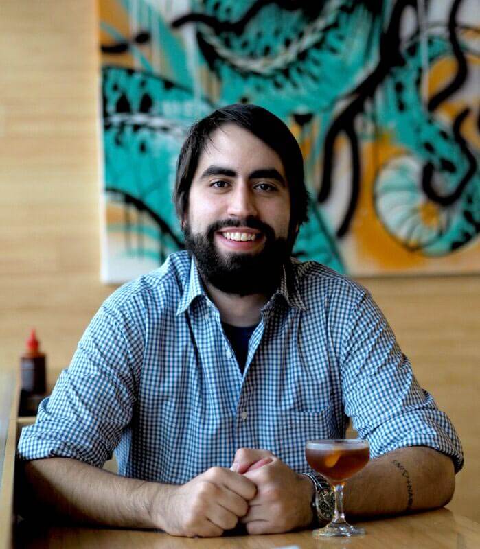 Jeff Spear, portrait with cocktail and painting in back