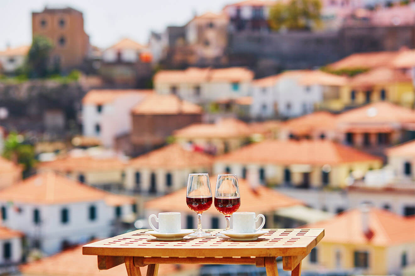 Two glasses of Madeira wine and two cups of fresh espresso coffee in cafe with view to Funchal town, Madeira, Portugal