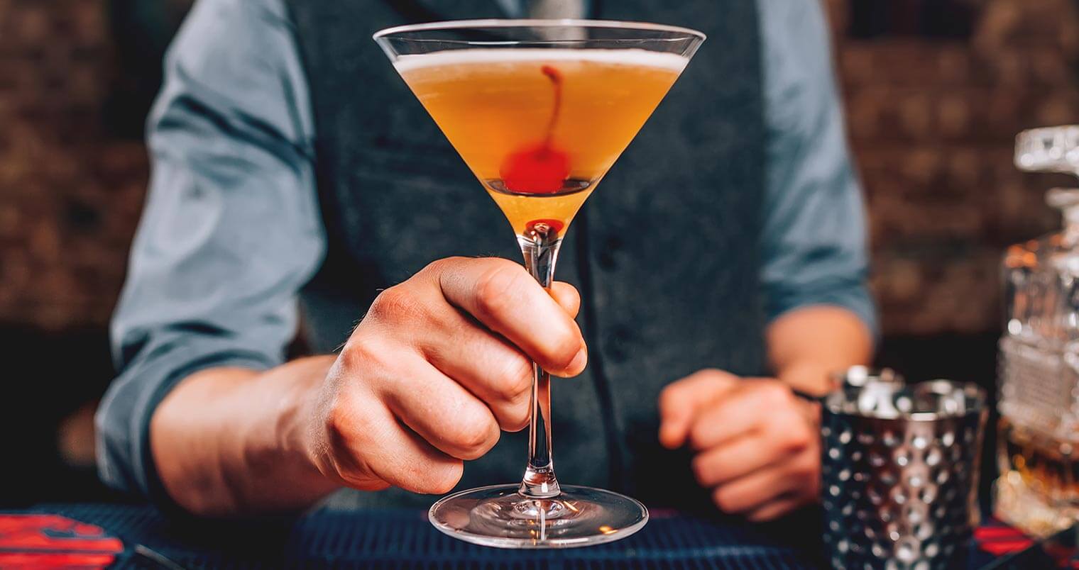 Manhattan Month 2018, bartender holding manhattan cocktail, featured image