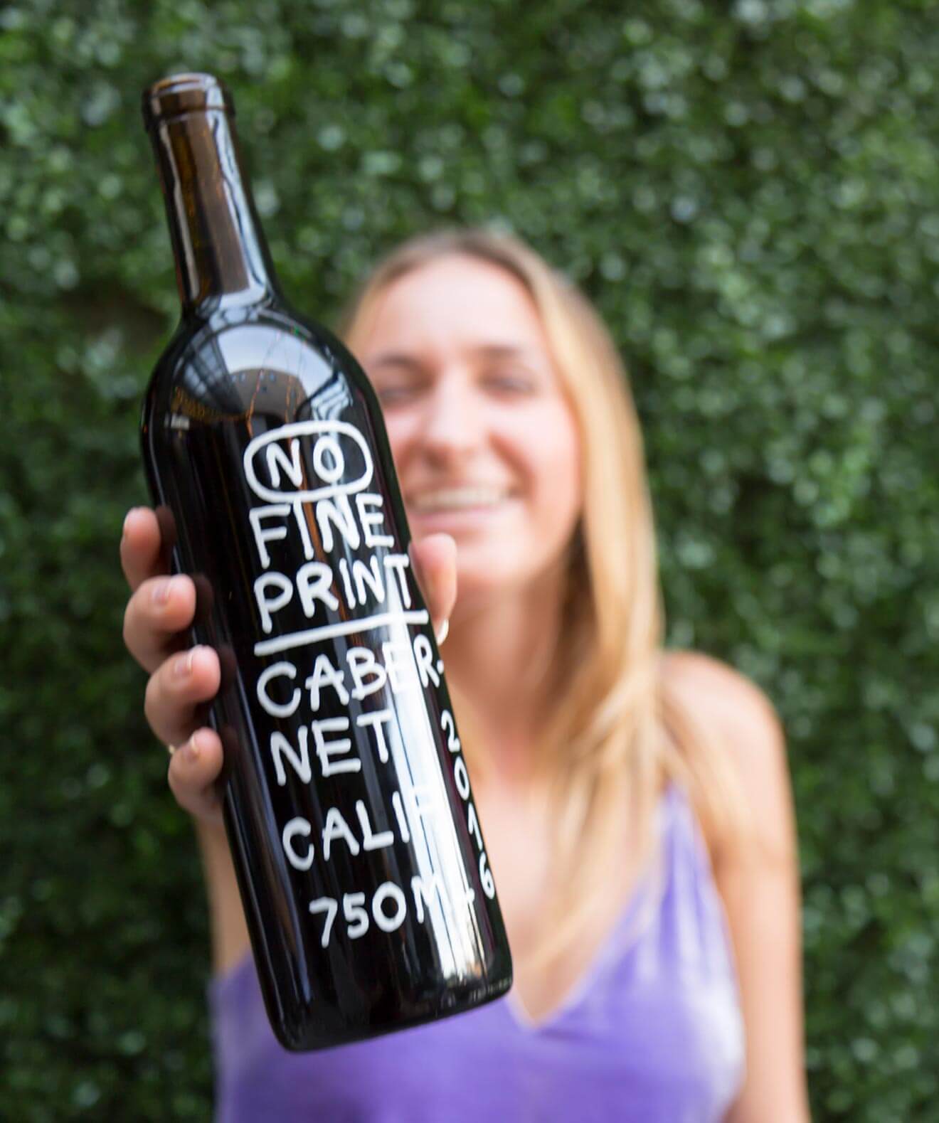 No Fine Print Wine, girl holding up bottle