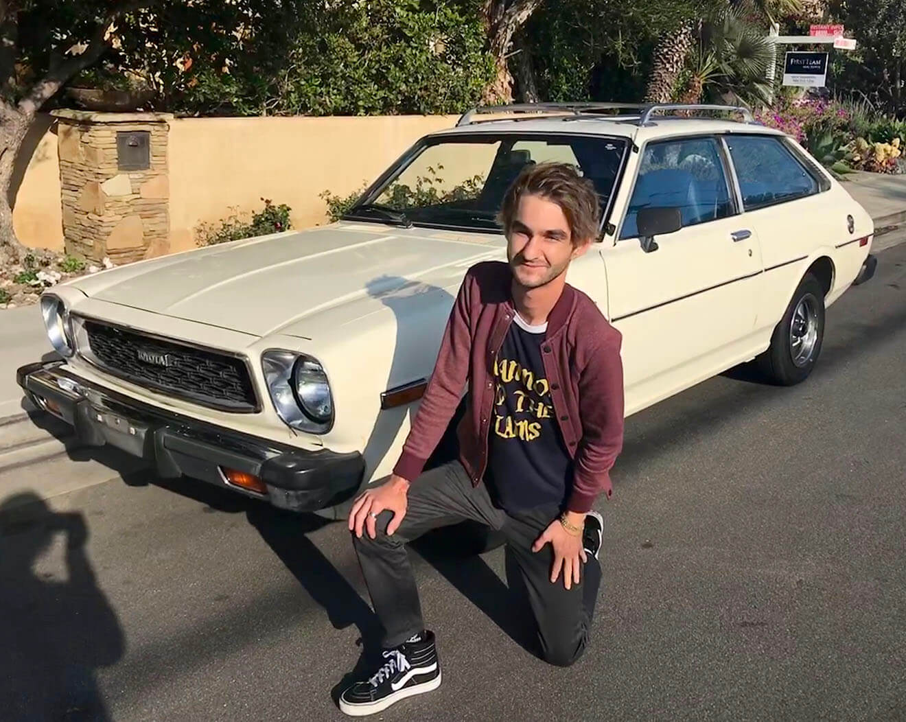 Perry Brown, Melrose Umbrella Company, kneeling in front of car