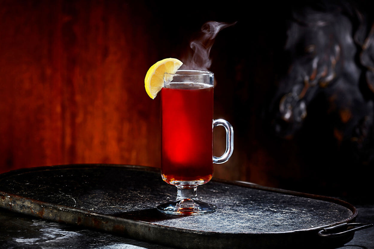 Rooibos Toddy, on dark background, cocktail with lemon garnish