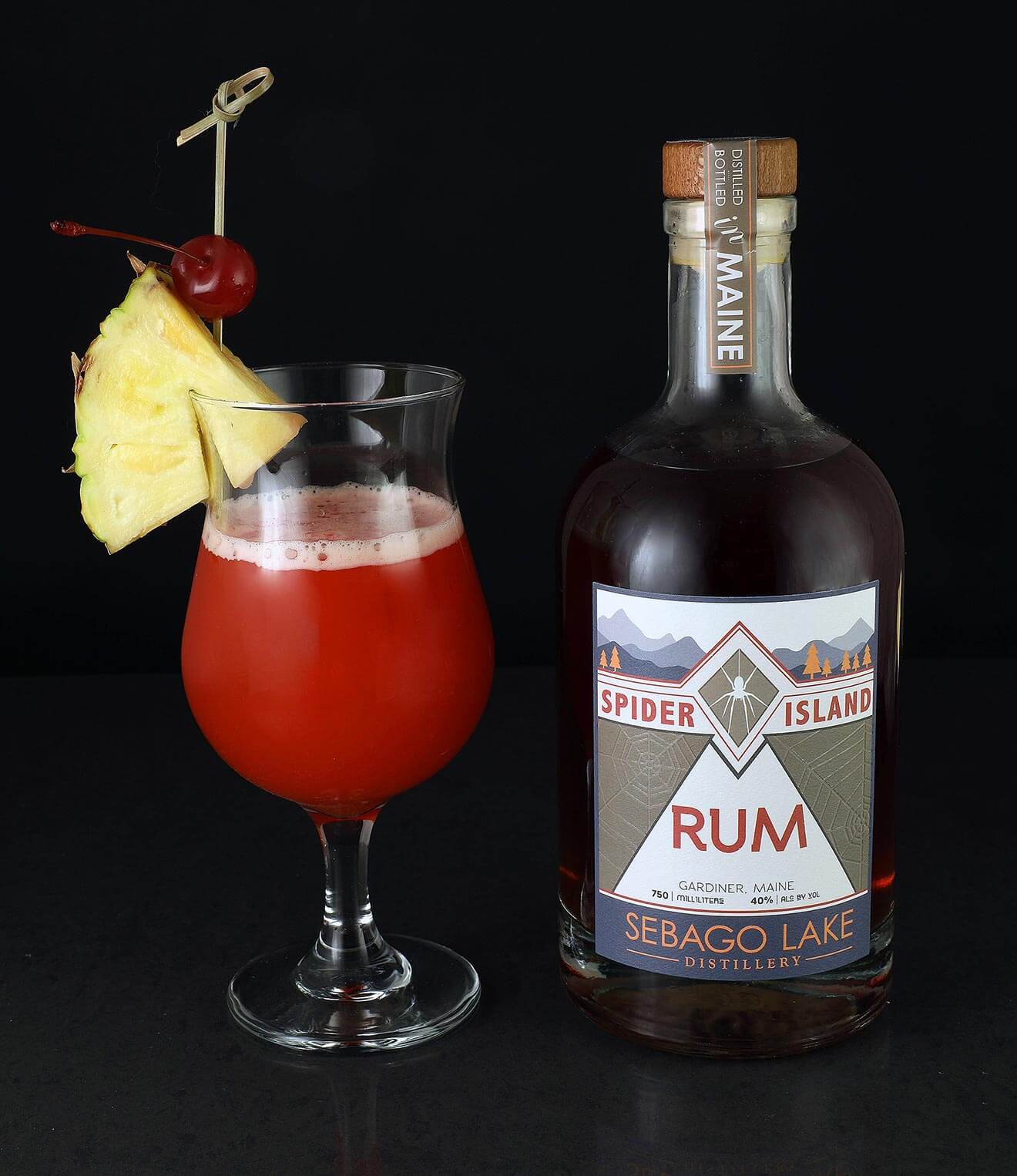 Spider Island Sling cocktail and bottle on dark background