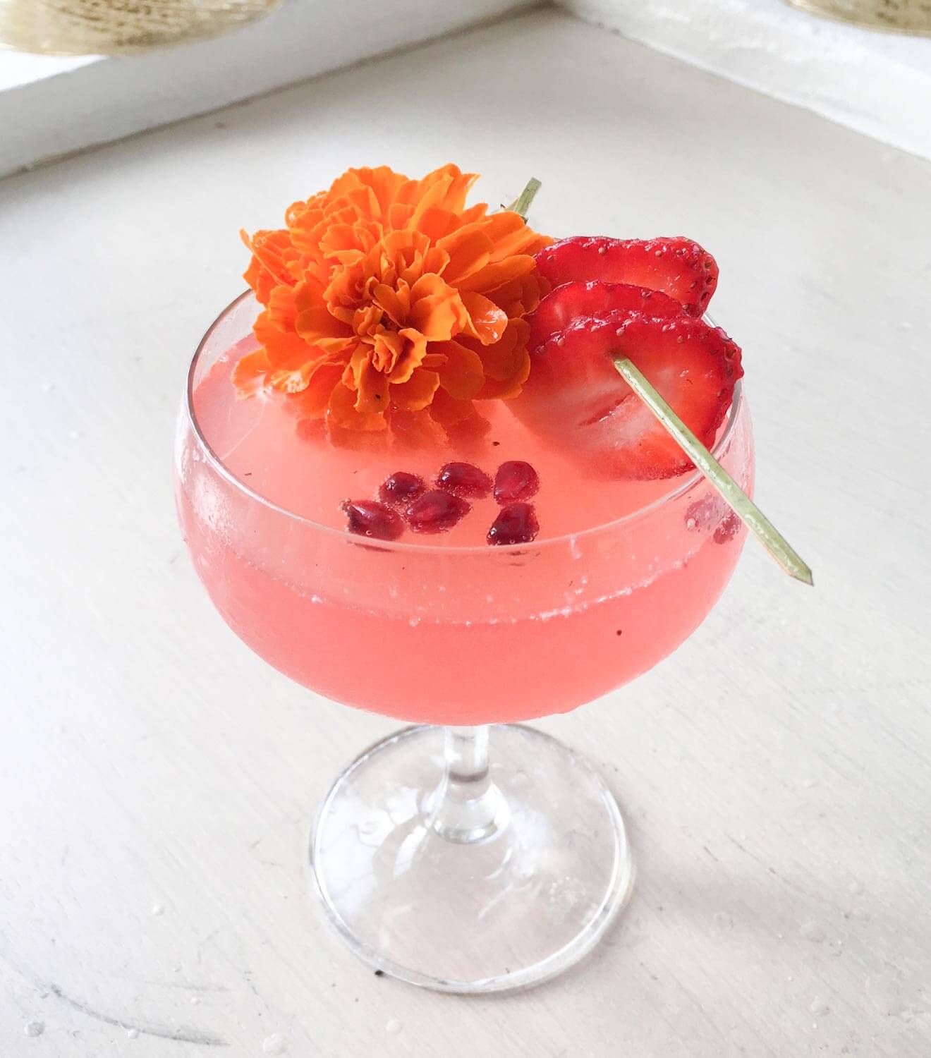 Strawberry Flirtini cocktail with strawberry and merrigold garnish