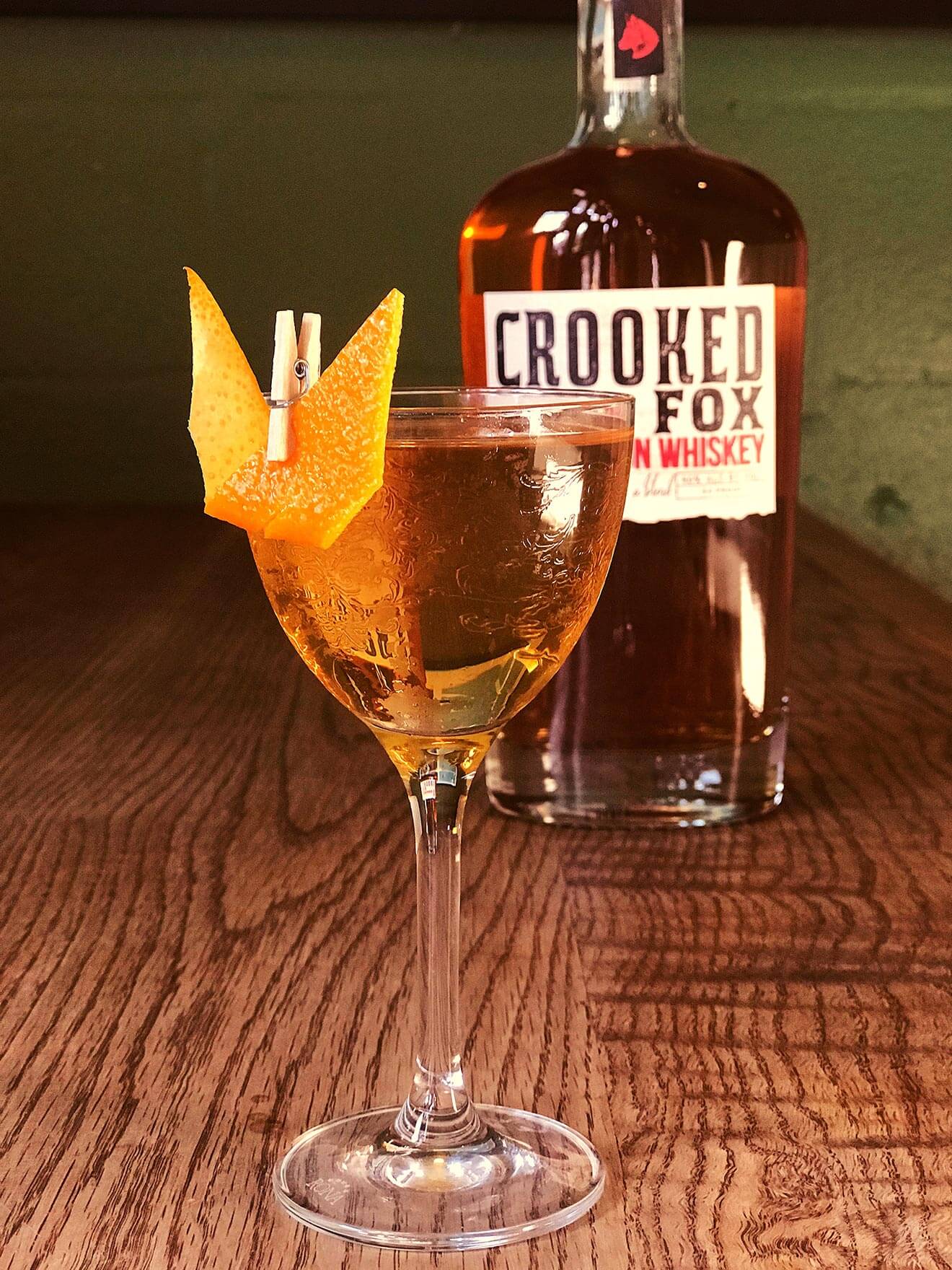 Tale of Two Foxes, cocktail and bottle on wooden table