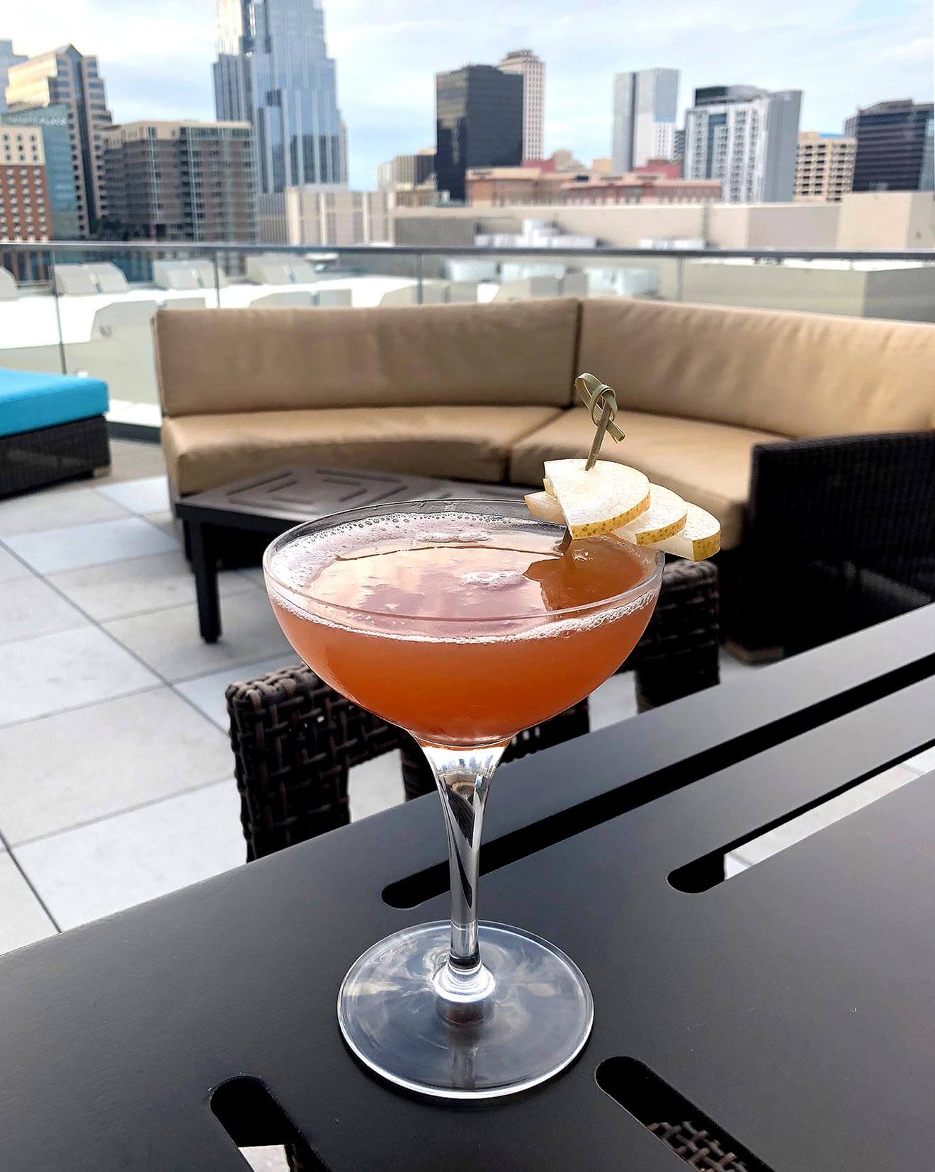 The Golden Hour cocktail on rooftop lounge, city background