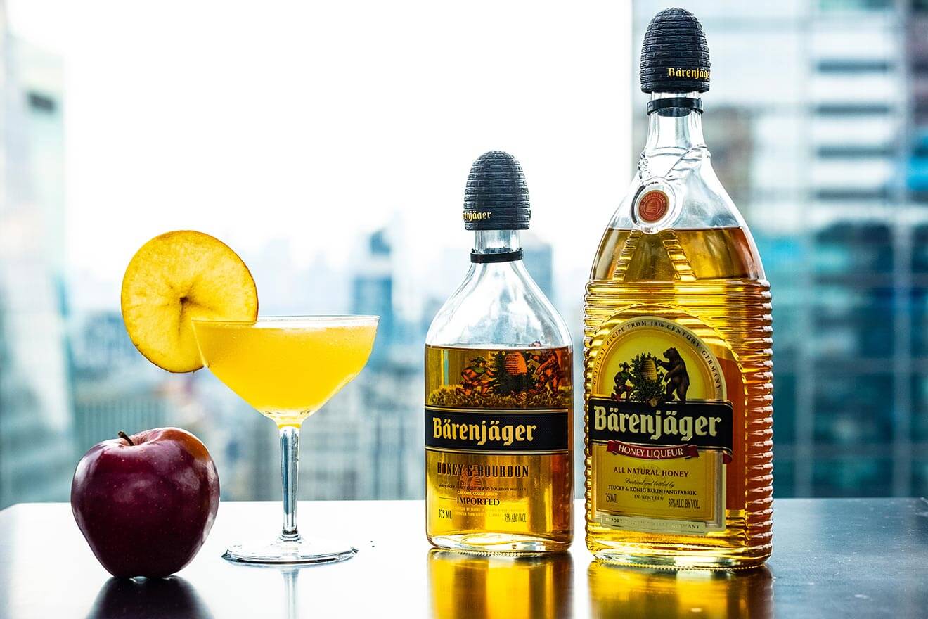 The Honey Crisp cocktail, bottles and garnished cocktials, city scape
