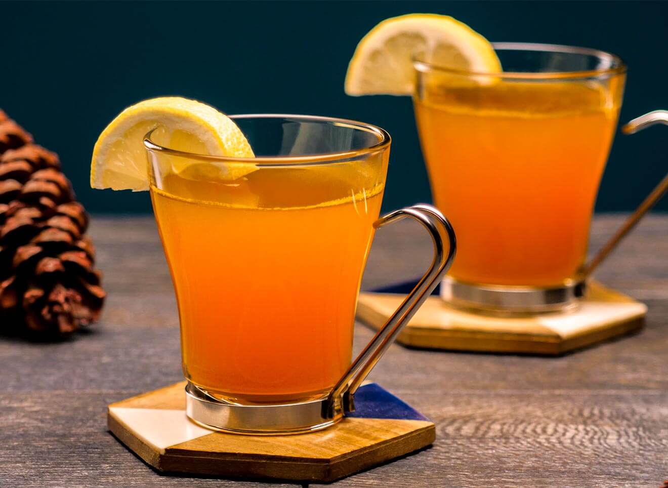 Turmeric-Ginger Hot Toddy, cocktails with lemon garnish, pinecone in back