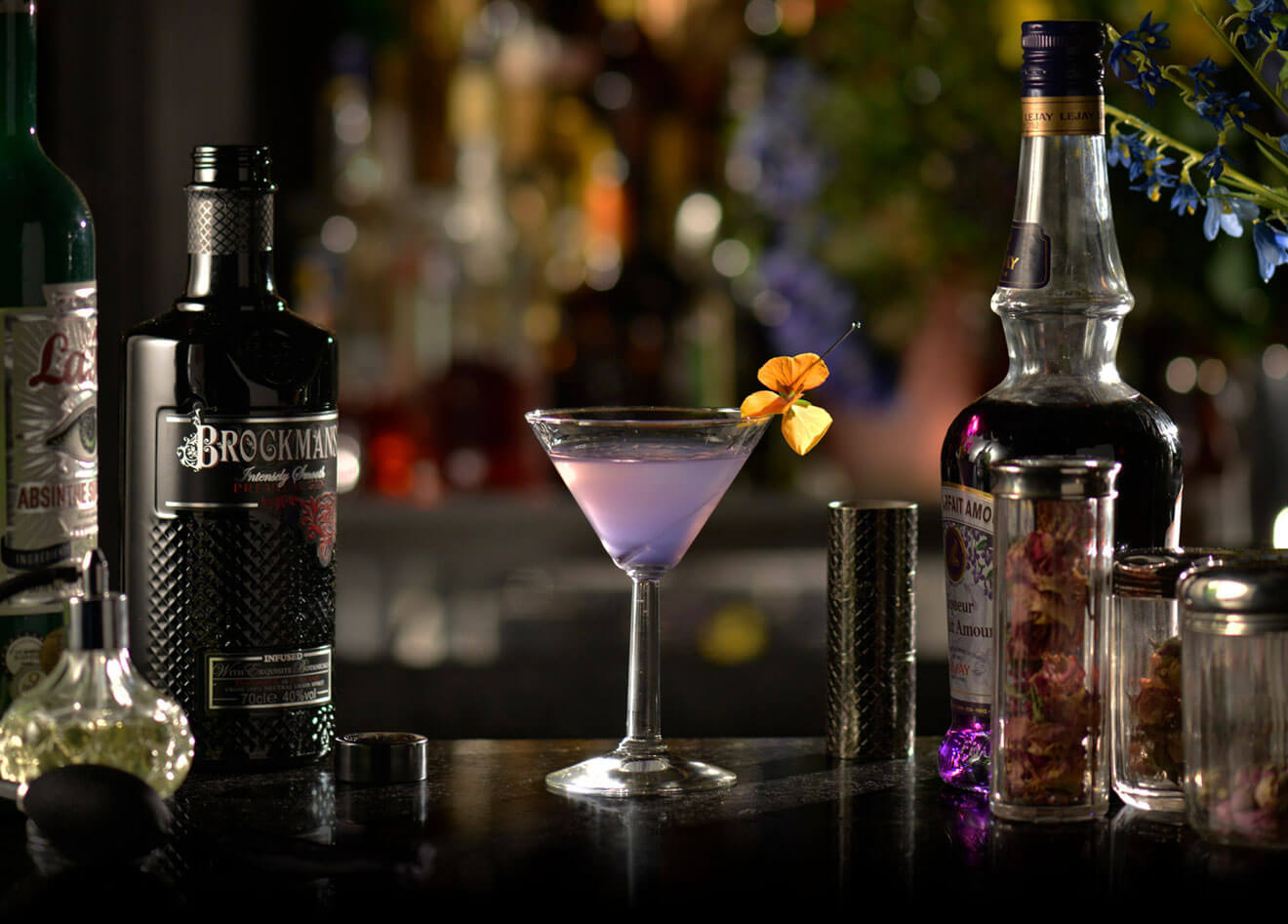 Ultra Violet, cocktail with garnishes, bottles on dark background