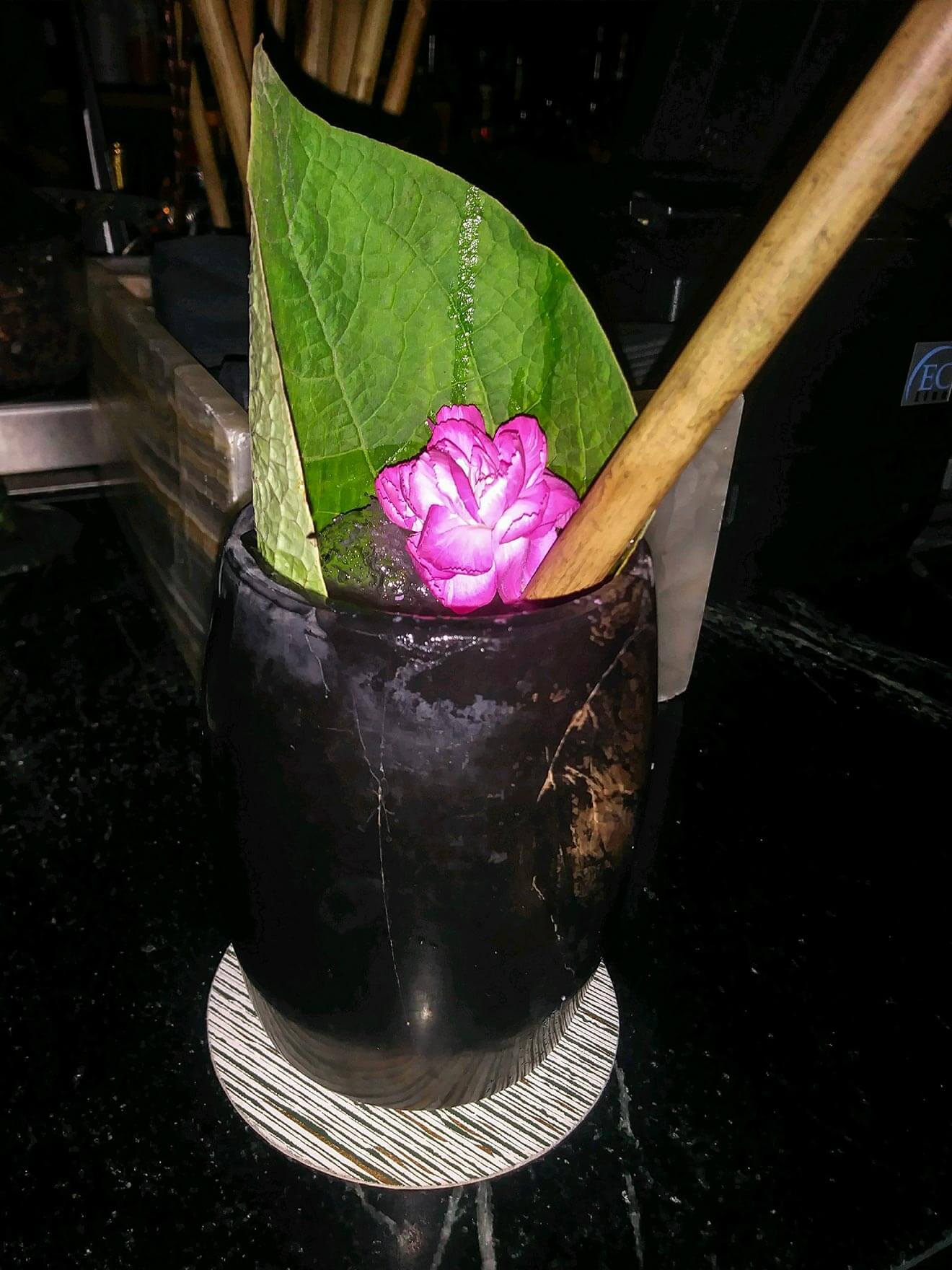 Xaman Cocktail with leaf and flower garnish