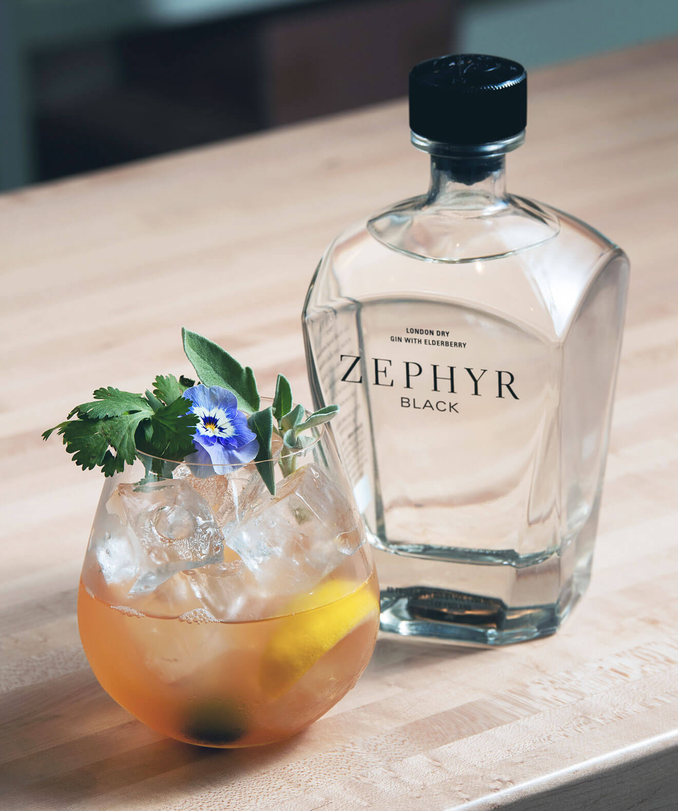 Zephyr Black Gin & Tonic, cocktail and bottle, wood table, angle overhead view