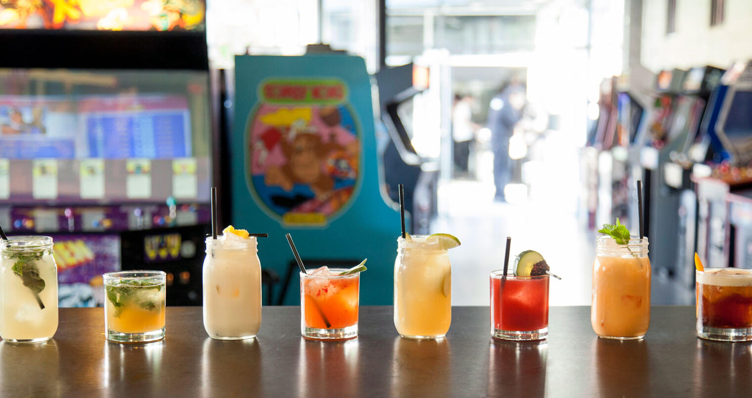 8 Awesome Arcade Bars, cocktails in a row, bar top in barcade
