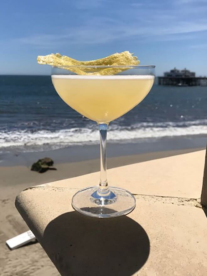 Bee's Knees 2019, cocktail with garnish, beach view in back