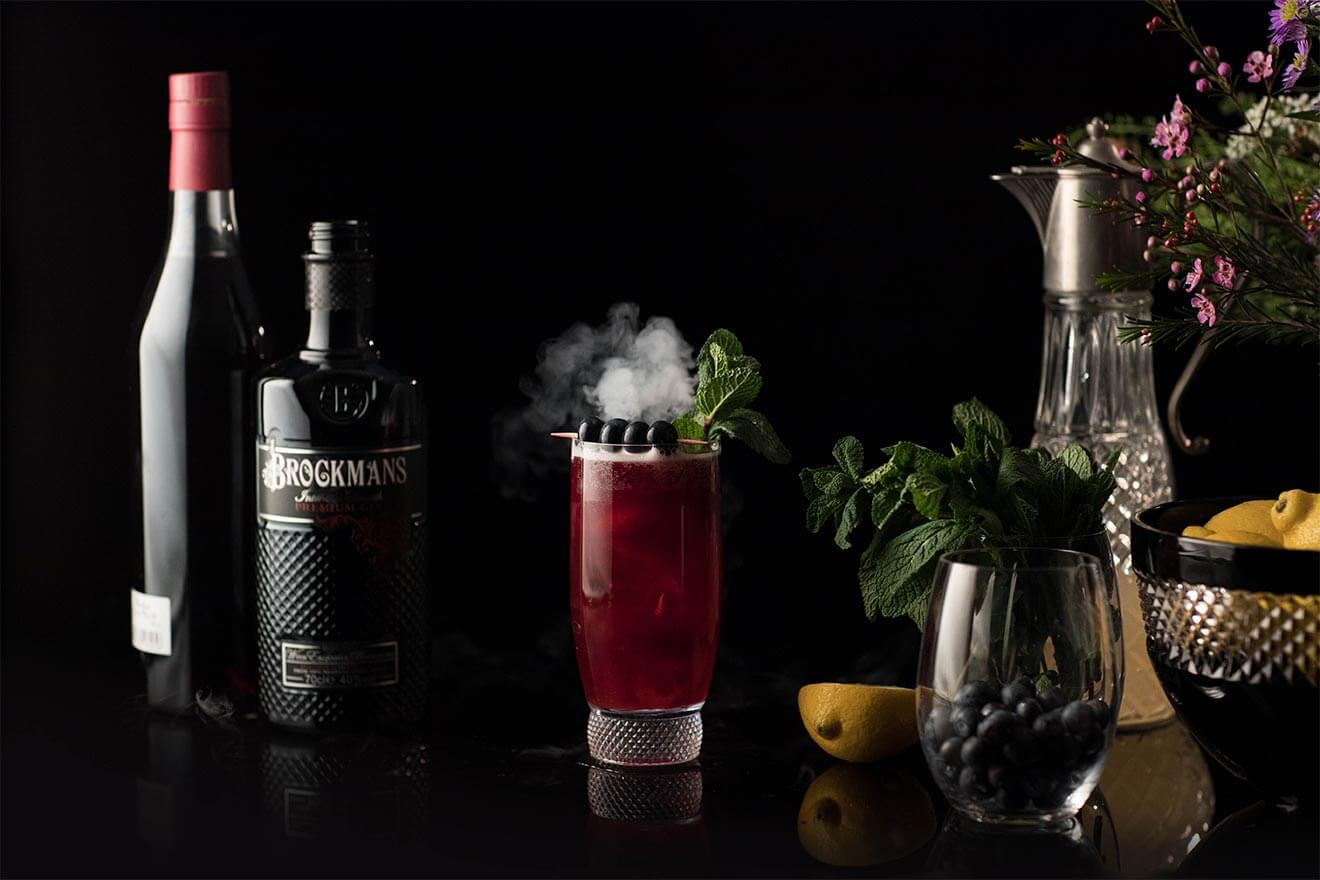 A cocktail next to a bottle of Brockmans gin