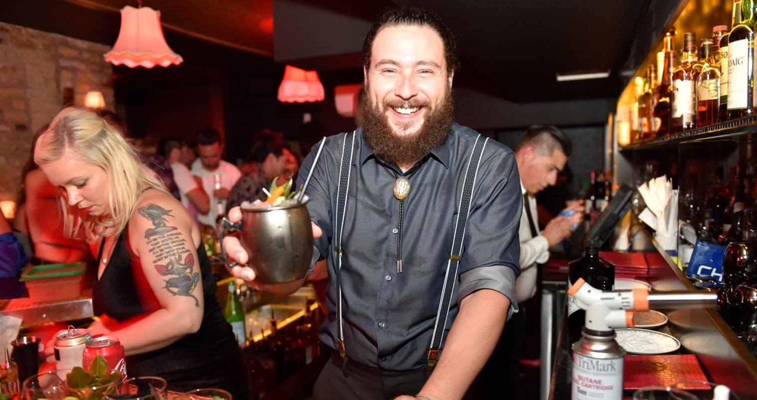 Justin Campbell, smiling behind the bar, featured image
