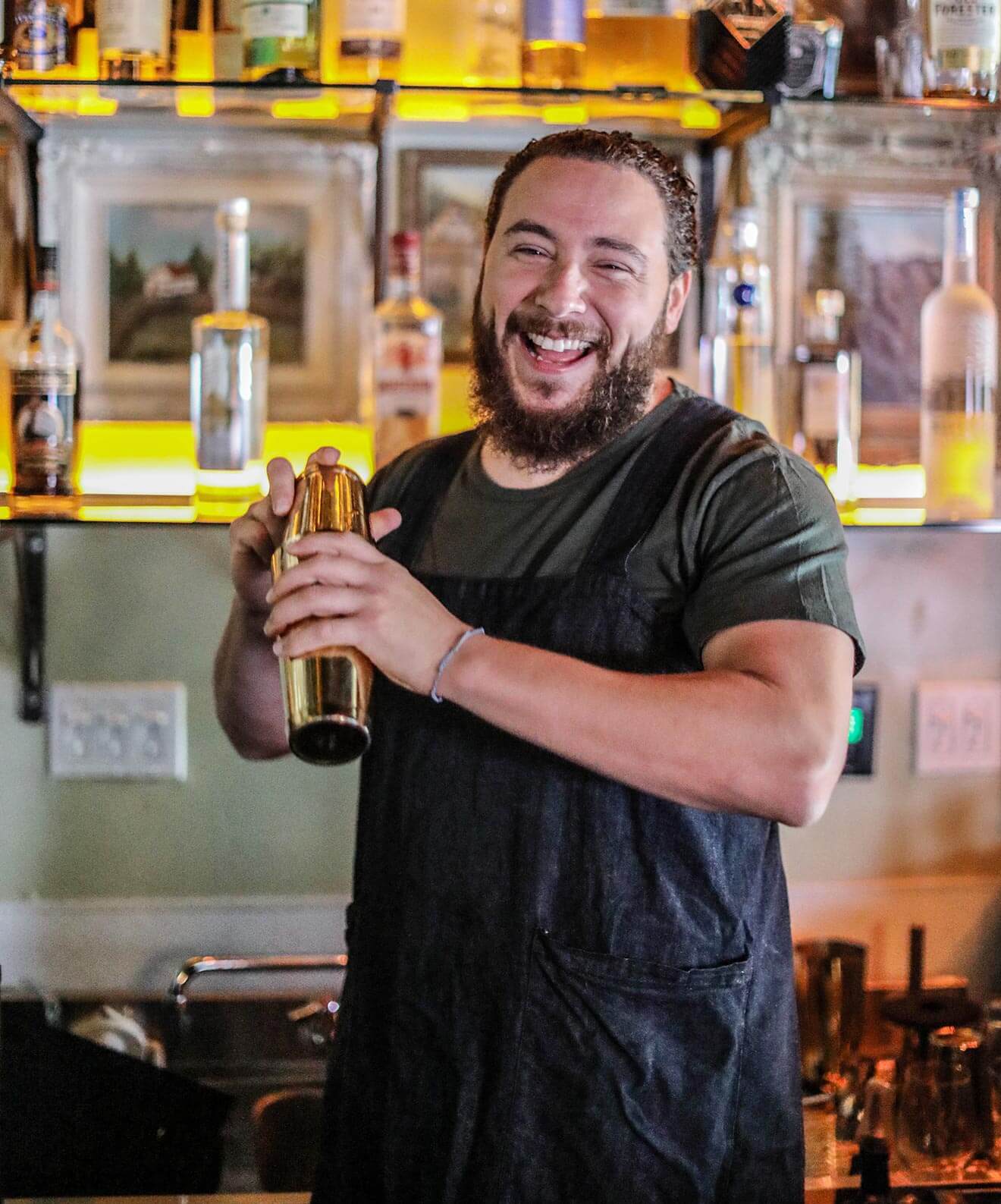 Justin Campbell smiling and mixing behind the bar