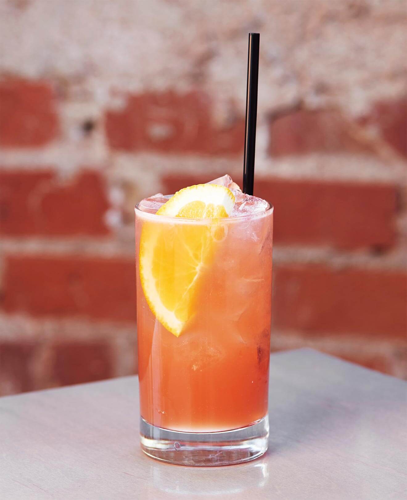 #1 Crush, cocktail with garnish and straw, brick wall background